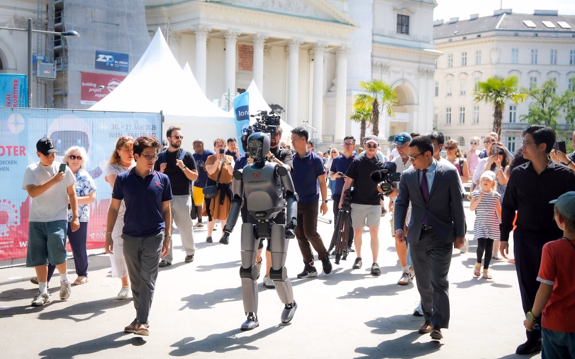 VR-H3 của VinRobotics thu hút sự chú ý với khả năng di chuyển tự nhiên tại Festival der Roboter 2026 ở Vienna, dưới sự chứng kiến của Đại sứ Việt Nam tại Áo, ông Vũ Lê Thái Hoàng (thứ hai từ phải sang, hàng trên), cùng đông đảo khách tham quan quốc tế. (Nguồn: VinRobotics)